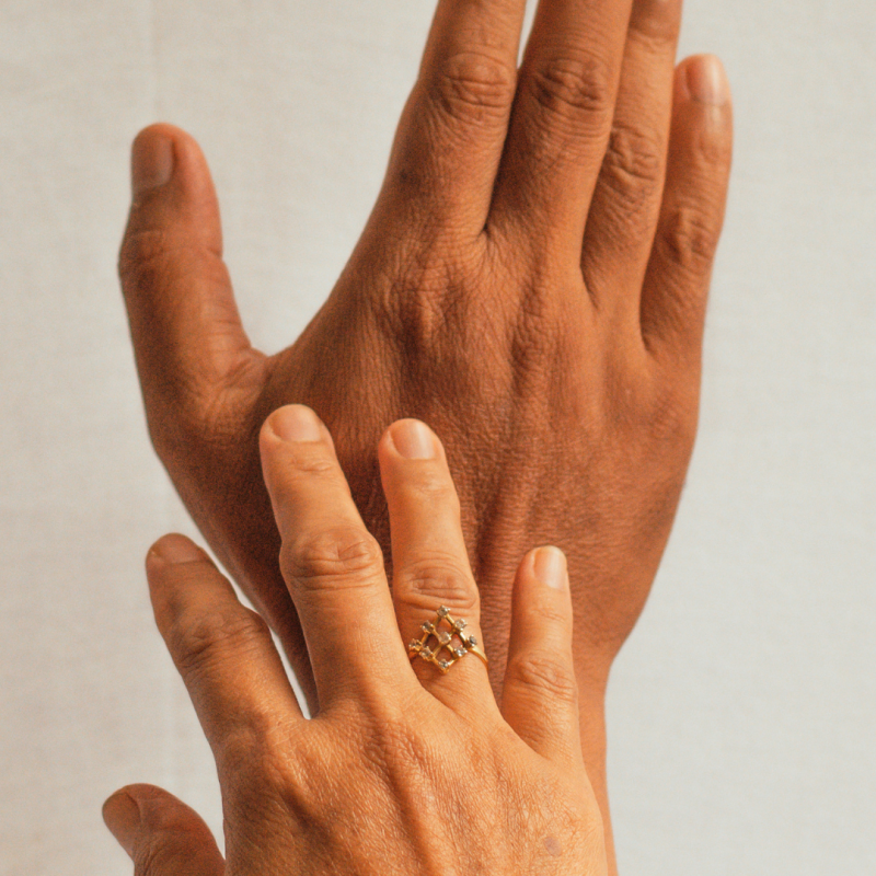 Two hands, one with a wedding ring, one without gently touching each other against a blank background.